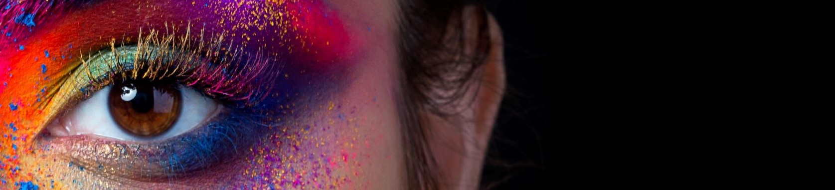 Picture of a brown eye with rainbow colors and glitter eyeshadow